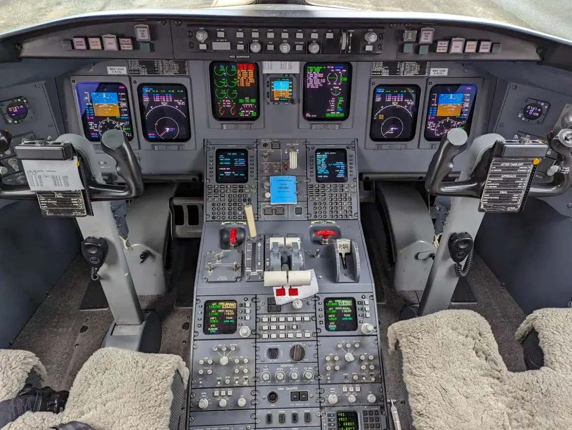 Cockpit d'avion moderne avec écrans d'avionique et vue sur une piste d'atterrissage au loin