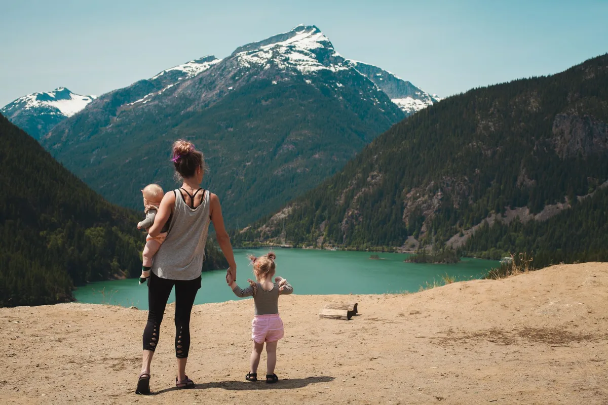 Famille de randonneurs avec enfants progressant ensemble sur un sentier forestier.