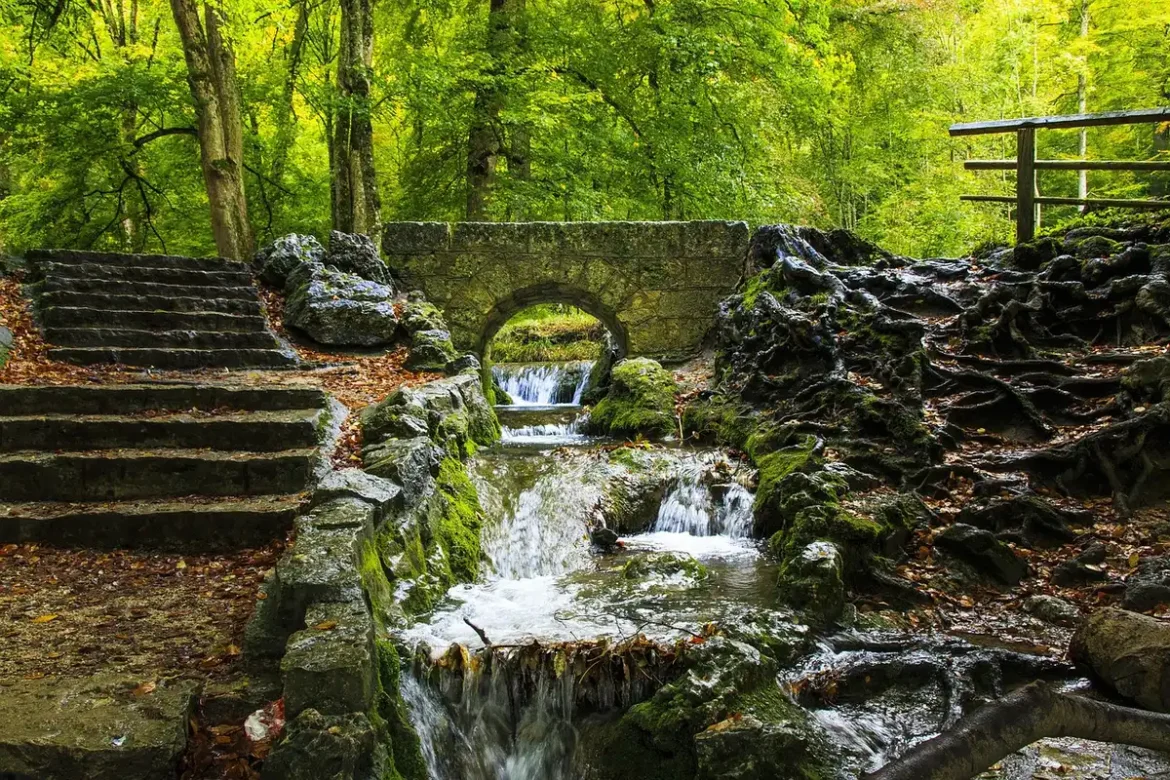 Randonneur solitaire descendant un sentier forestier vers une cascade cachée en Méditerranée