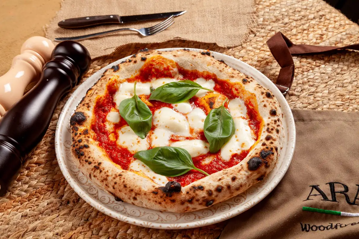 Pizza napolitaine traditionnelle sortant d'un four à bois, pâte gonflée et garniture simple