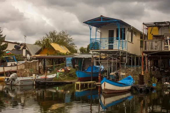 Bateau naviguant dans un delta fluvial avec habitations sur pilotis et végétation luxuriante