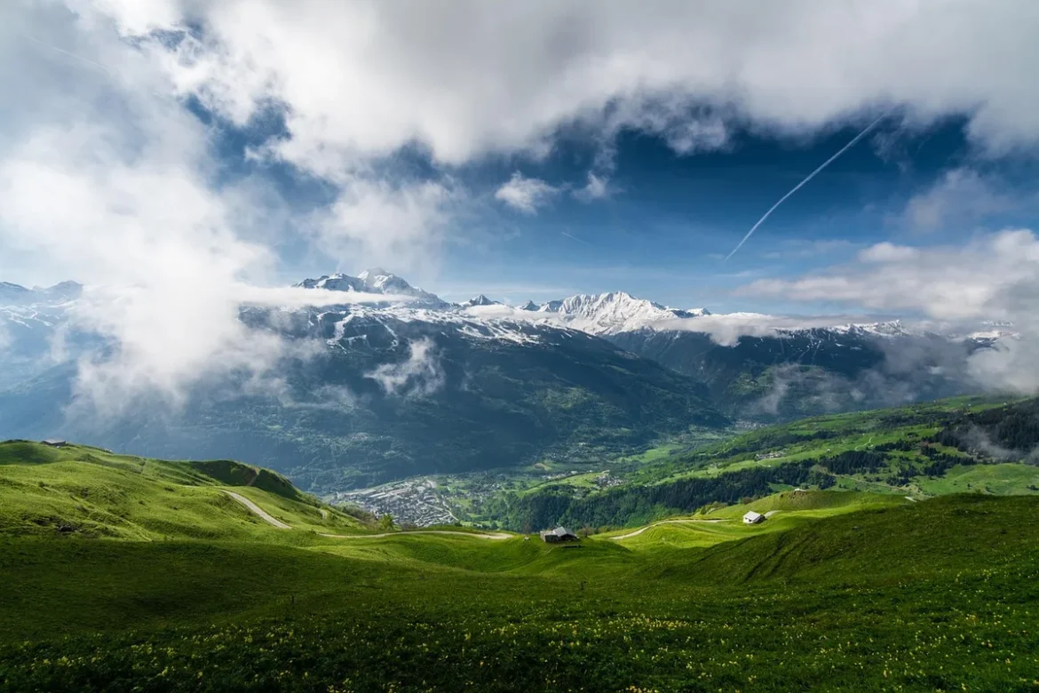 Randonneur solitaire sur sentier alpin brumeux avec vue sur vallée glaciaire et sommets lointains