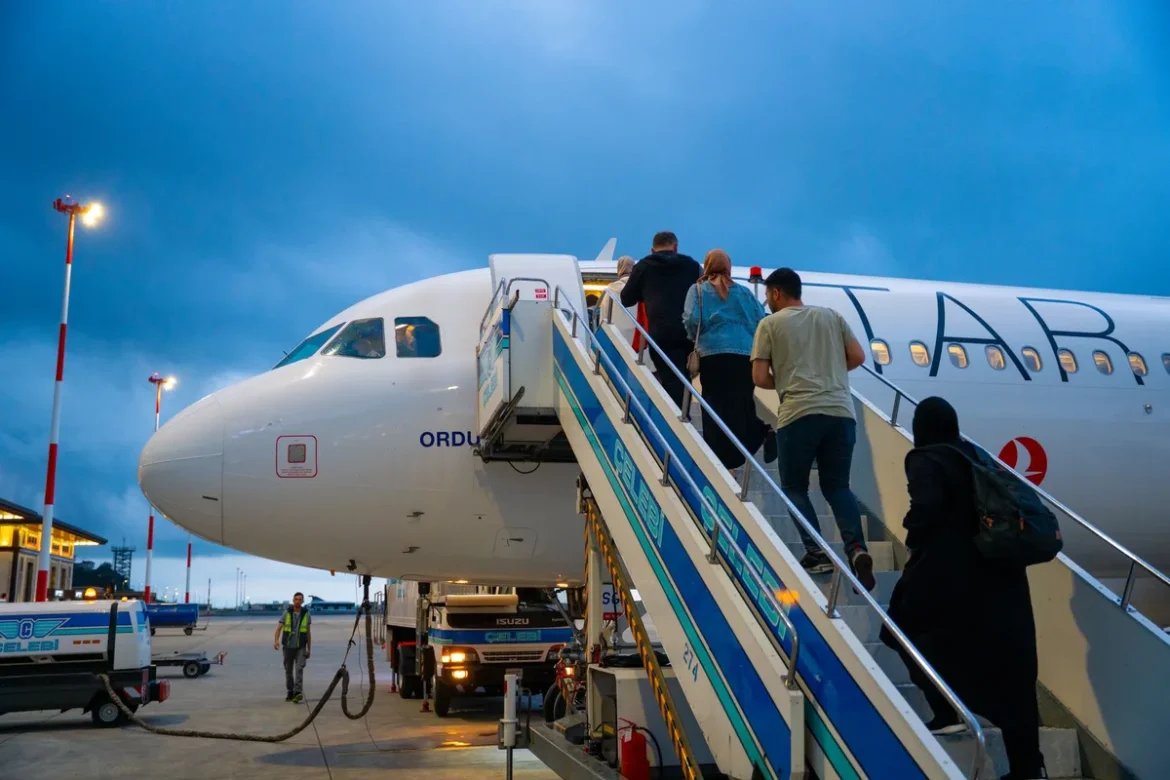 Voyageurs dans un terminal d'aéroport consultant les tableaux des départs, avec bagages