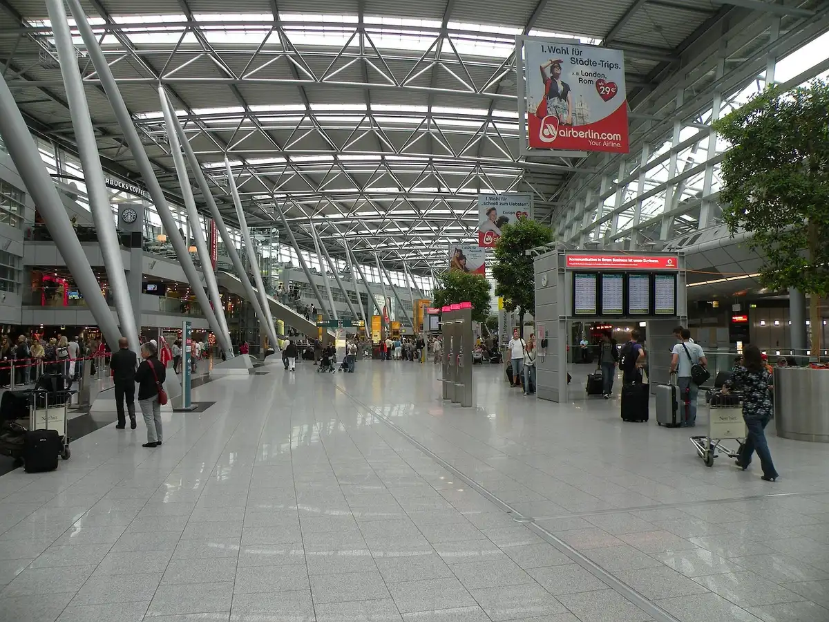Hall lumineux d'un terminal montrant plusieurs portes et passagers en journée