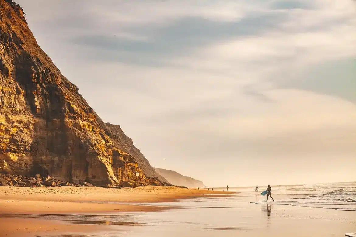 Surfeur chevauchant une vague creuse devant des falaises ocres en Algarve