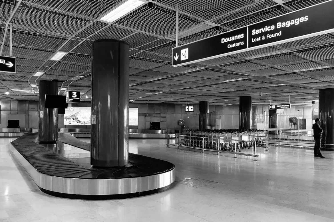 Silhouette d'un avion monocouloir au sol devant un terminal, valises au premier plan