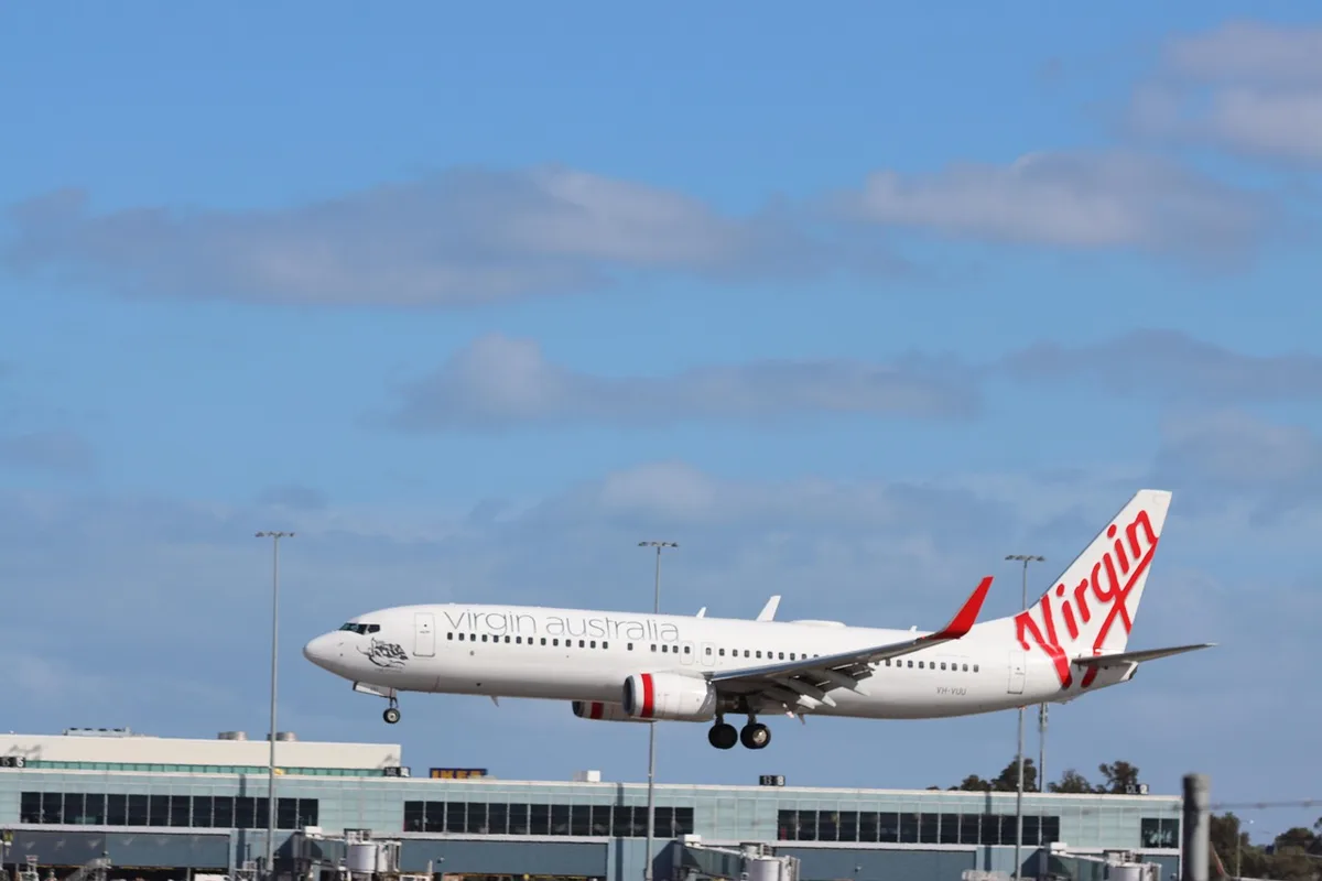 Un Boeing 737 stationné à une porte d'embarquement en journée