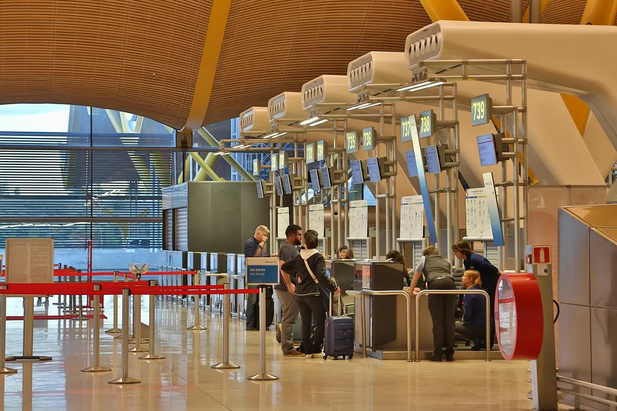 Comptoir d'enregistrement montrant des bagages et un agent aidant à l'enregistrement en correspondance