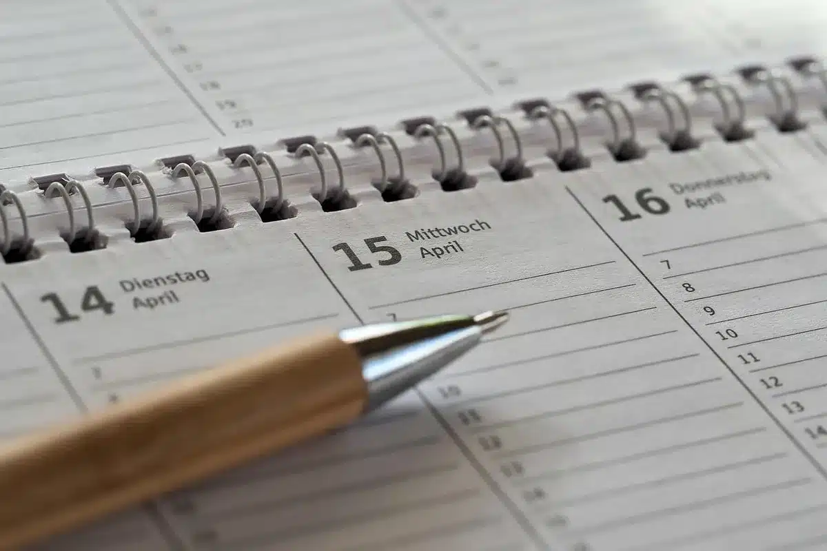 Calendrier mois par mois posé sur un bureau avec notes de voyage